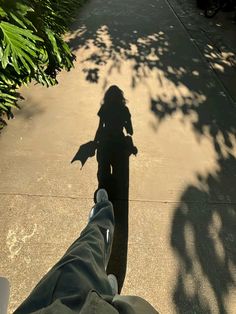 the shadow of a person's feet and leg on a sidewalk with trees in the background