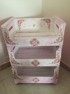 a baby crib with pink flowers painted on the sides and bottom shelf, sitting against a wall