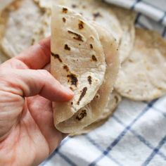 a hand is holding some tortillas on a towel