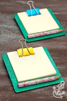 two binders with paper clips attached to them sitting on a wooden table next to a pair of scissors