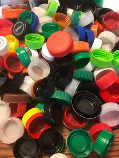 there are many different colored plastic caps on the wooden table and one is black, white, red, green, yellow, orange