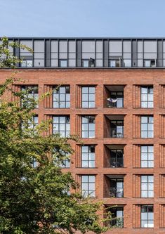 a tall brick building with lots of windows and balconies on the top floor