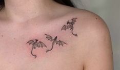 a woman's chest with three small dragon tattoos on her upper arm and shoulder