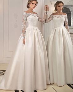 two women in wedding gowns standing next to each other with their hands on the wall