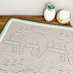 a crocheted blanket sitting on top of a wooden table next to a potted plant