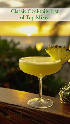 a glass filled with a yellow liquid next to a pineapple