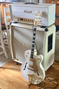 an electric guitar sitting on top of a hard wood floor next to a amplifier and amp