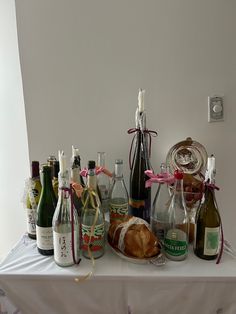 several bottles of wine and bread on a table with ribbon around the edges, in front of a white wall