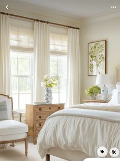 a white bed sitting in a bedroom next to a window covered in curtains and pillows