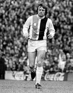 an old photo of a soccer player running on the field in front of a crowd