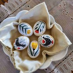 four painted eggs sitting on top of a white plate