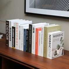 a row of books sitting on top of a wooden table next to a framed photo