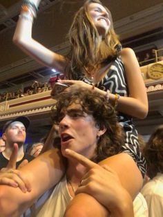 a woman sitting on top of a man's shoulders in front of a crowd