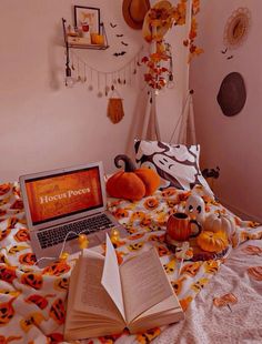 an open laptop computer sitting on top of a bed covered in pumpkins and decorations