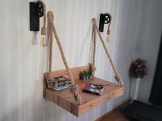 two wooden shelves with rope hanging from them and some books on the shelf next to them