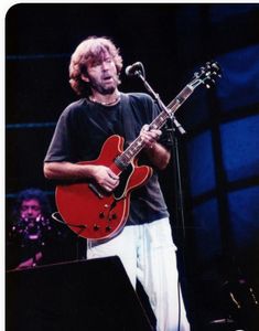 a man holding a red guitar while standing in front of a microphone