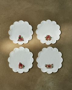 four white paper coasters with bows and presents on them, sitting on a table