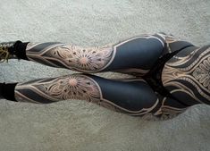 a woman with tattoos on her legs and leggings is standing in the floor