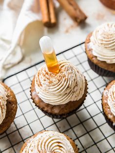 cupcakes with frosting and cinnamon sticks on a cooling rack