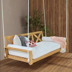 a wooden swing bed with pillows on it