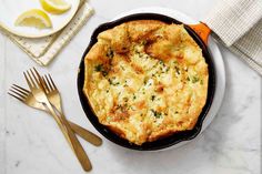 an omelet in a cast iron skillet on a white table with silverware