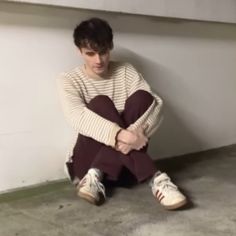 a young man sitting on the floor with his arms crossed