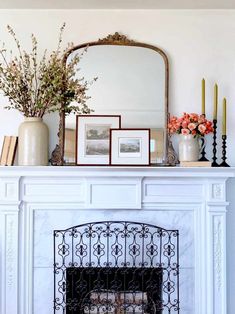 a white fireplace with flowers and pictures on top