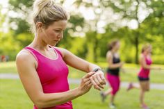 a woman in pink shirt and black shorts standing on grass with other people behind her