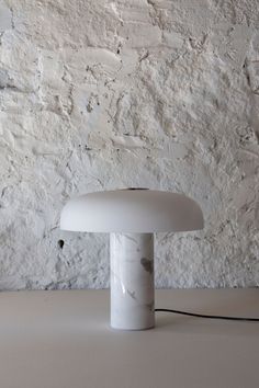 a white lamp sitting on top of a table next to a wall with peeling paint