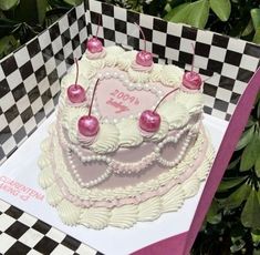 a birthday cake with cherries on it sitting in front of a checkered box