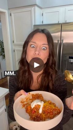 a woman is holding a bowl of food in her hands and looking surprised at the camera