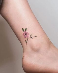 a small flower tattoo on the ankle is shown in this image, it shows pink flowers and green leaves