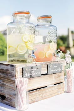 two mason jars filled with lemonade sit on top of a wooden crate at an outdoor wedding