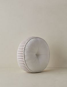 a round pillow sitting on top of a white floor next to a brown and white wall