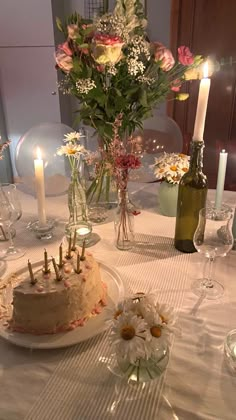 a table topped with a cake covered in frosting next to wine glasses and flowers