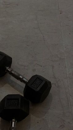 two black dumbbells sitting on top of each other in front of a wall