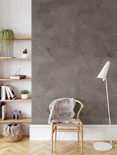 a chair in front of a gray wall with bookshelves and a floor lamp