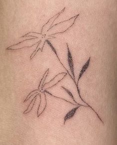 a small flower tattoo on the side of a woman's thigh, with leaves