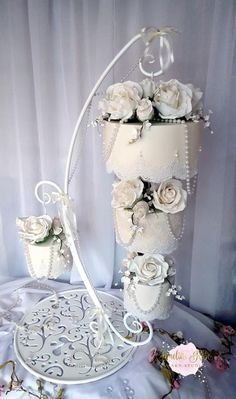 a wedding cake with white flowers and pearls on the top is sitting on a table