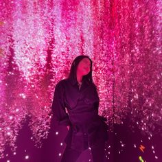 a woman standing in front of a wall with pink and purple lights on it's walls