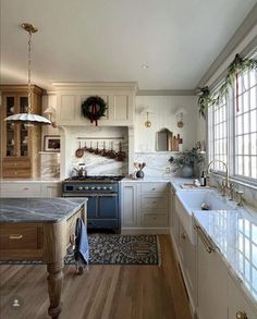 a kitchen with wooden floors and white cabinets, an island countertop and blue appliances