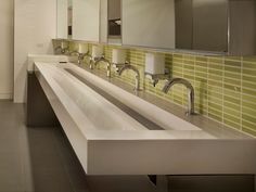 a bathroom with two sinks and green tile on the wall behind it is a large mirror