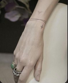 a woman's hand with a small star tattoo on her left wrist and ring