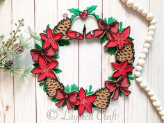 a christmas wreath with poinsettis and pine cones hanging on a white wall