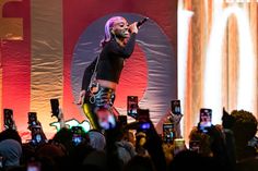 a woman standing on top of a stage holding a microphone in front of a crowd