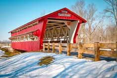 a red covered bridge with snow on the ground