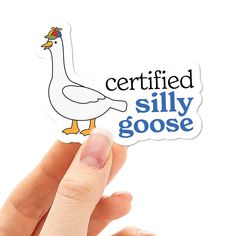 a person holding up a sticker with a duck on it that says certified silly goose