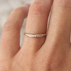 a woman's hand with a gold band and diamond ring on her left hand