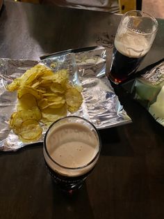 some food is laying out on the table next to a glass of beer and chips