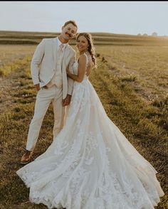 a bride and groom posing for a photo in the middle of an open grassy field